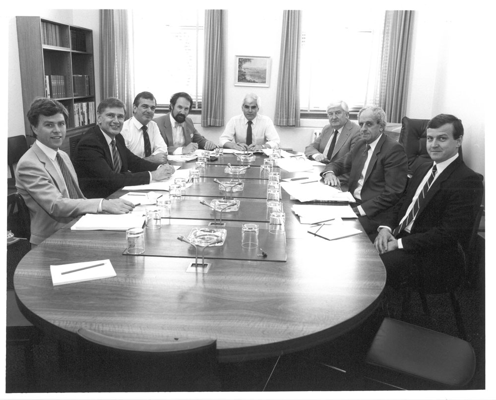 Standing Committee on Finance and Public Administration, December 1987. L-R: John Needham [Research Officer], Senators Richard Alston and Paul Calvert, John Nethercote [Secretary], Senators John Coates [Chair], Peter Durack, Bryant Burns and John Black.