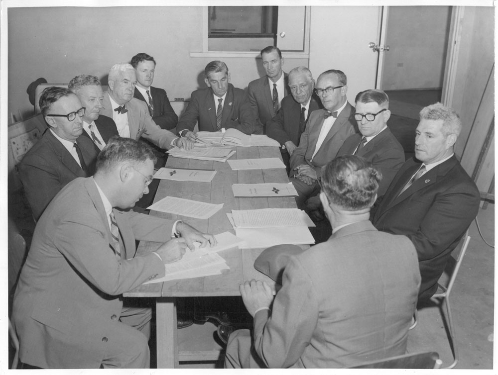Members of the Select Committee on Road Safety hearing evidence from a witness at a public hearing in the boardroom of Safety House, headquarters and instructional centre of the National Safety Council of Western Australia, Mount Lawley, WA, 12 February 1960. Clockwise around table from top: Senator Kenneth Anderson [Chair], W. O’Brien [Research Officer], Senators Jim Sheehan, Justin O’Byrne, Harrie Wade and Arnold Drury, witness R.G. Clark [Executive Director, National Safety Council of WA], a Hansard reporter, Senators Frank McManus, Malcolm Scott and Neil O’Sullivan, and Alan Cumming Thom [Secretary].