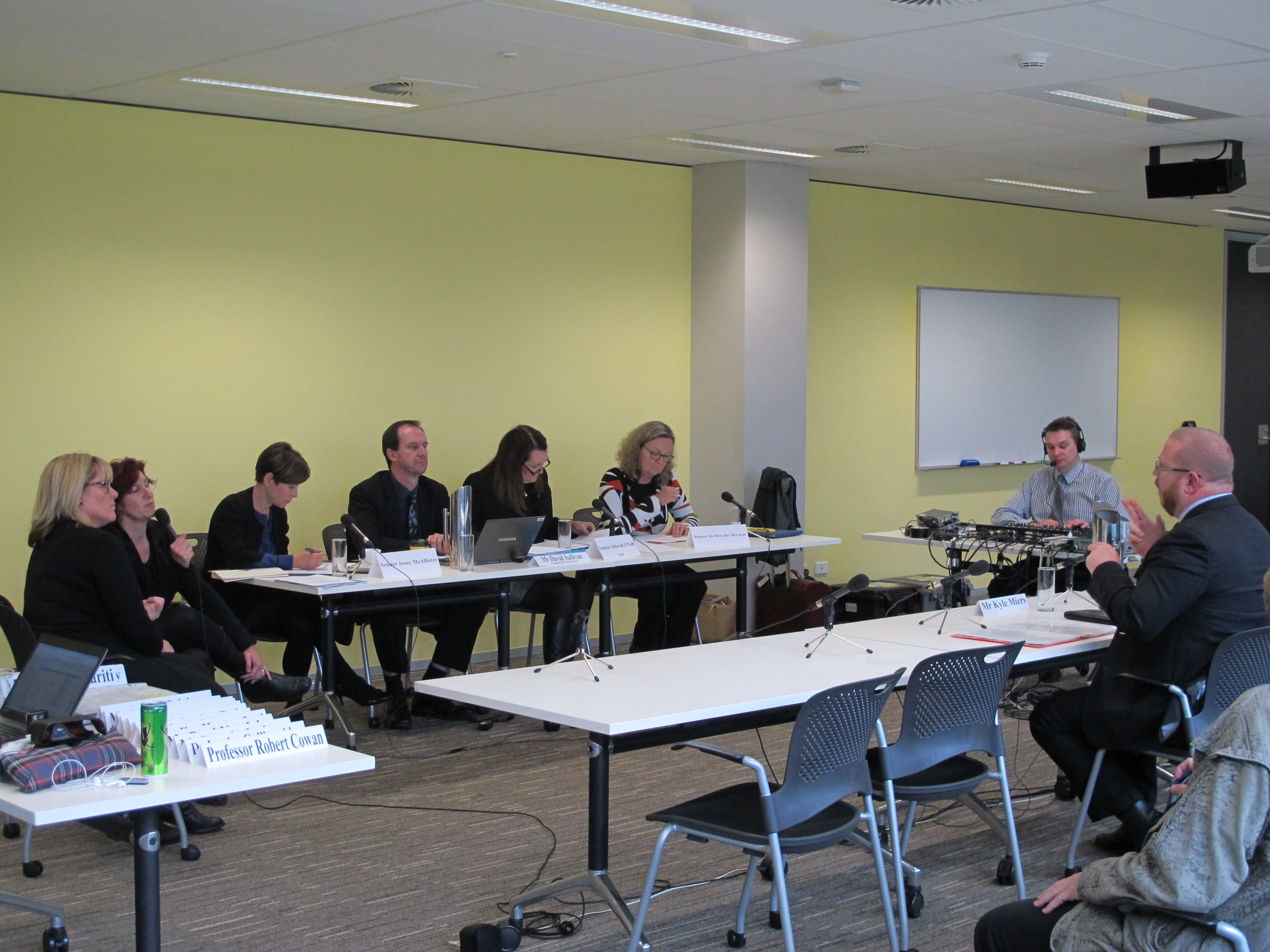 Committee members hearing evidence from witness Kyle Miers, CEO of Deaf Australia, at a public hearing at the Australian Hearing Hub, Macquarie University, on deaf and hearing impairment health issues, 10 July 2015. Mr Miers signed his evidence to the interpreters, one of whom translated into spoken word for the committee while the other signed the committee's questions to Mr Miers. L-R: Two Auslan interpreters, Senator Jenny McAllister, David Sullivan [Acting Secretary], Senators Deborah O'Neill and Jan McLucas, a Hansard editor and witness Kyle Miers.
