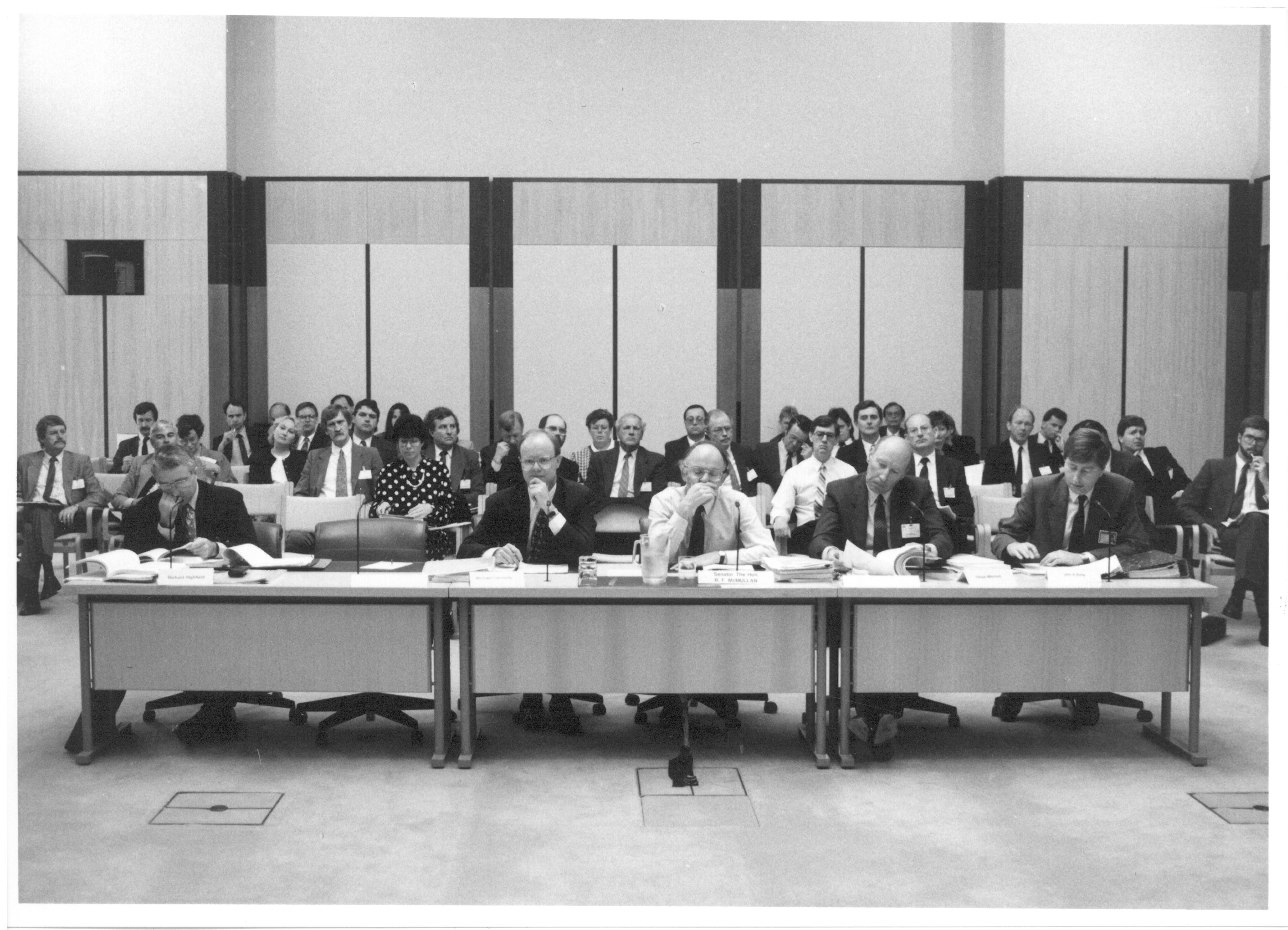 \x3cp\x3eSenator the Hon Bob McMullan, Parliamentary Secretary to the Treasurer, appearing with officers from the Australian Taxation Office before Estimates Committee A, 11 October 1991. Seated L-R: Witnesses Richard Highfield [First Assistant Commissioner, Revenue Collection], Michael Carmody [Second Commissioner of Taxation], Senator Bob McMullan [Parliamentary Secretary to the Treasurer], Vince Mitchell [First Assistant Commissioner, Taxpayer Audit] and Jim Killaly [Acting Chief Tax Counsel].\x3c/p\x3e