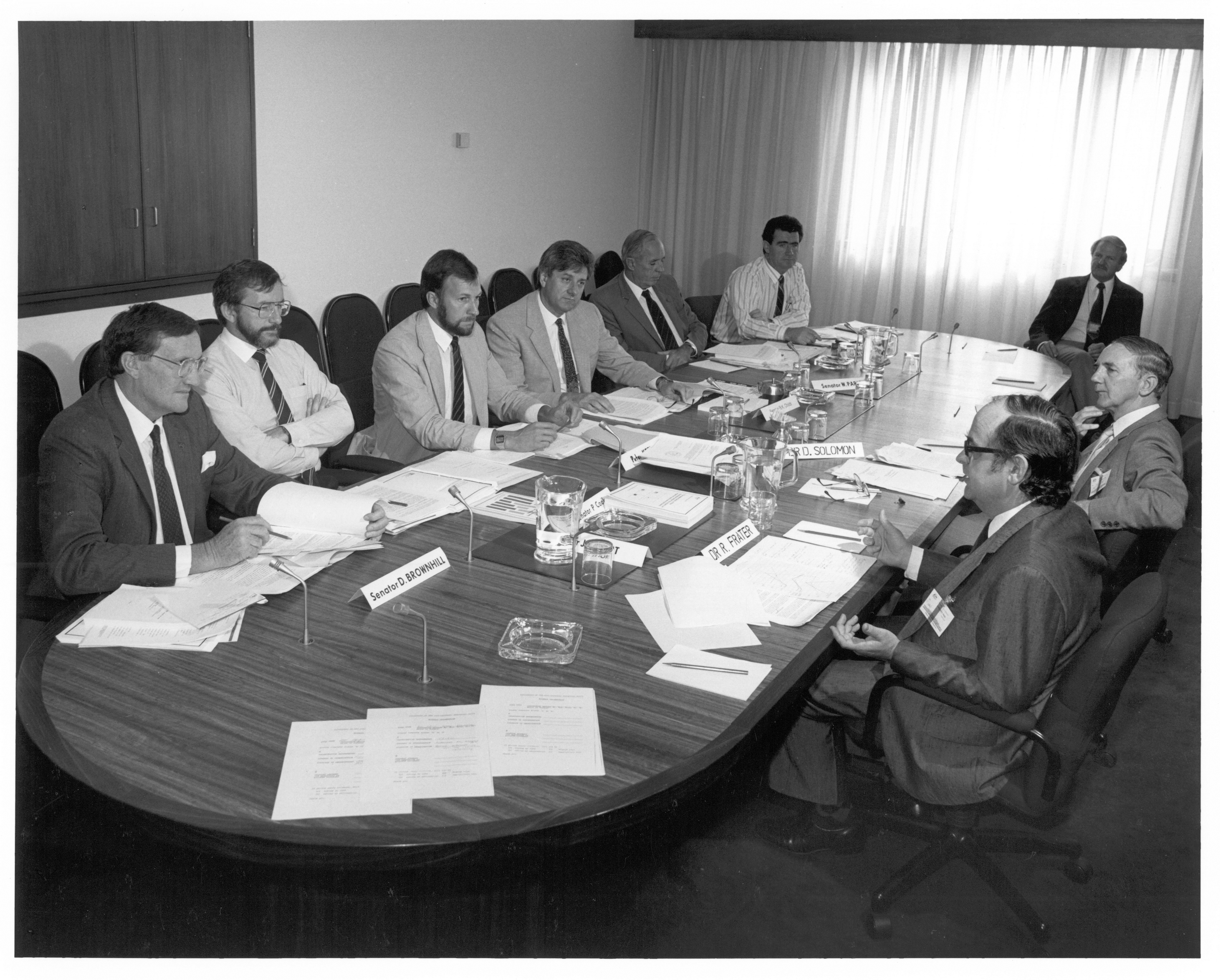 \x3cp\x3eStanding Committee on Industry and Trade, 26 March 1987. Clockwise around table from left: Senators David Brownhill and Peter Cook, Peter Keele [Secretary], Senators Bruce Childs [Chair], Warwick Parer and Jim McKiernan, Michael Game [Research Officer], witnesses Dr David Solomon [Acting Director, Institute of Industrial Technology, CSIRO] and Dr Robert Frater [Chief of the Division of Radiophysics, CSIRO]. NAA: A6180, 31/3/87/66.\x3c/p\x3e